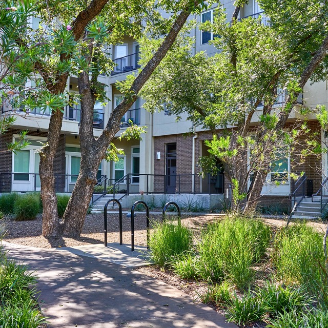 The exterior of the community with a walking path, trees, and bushes