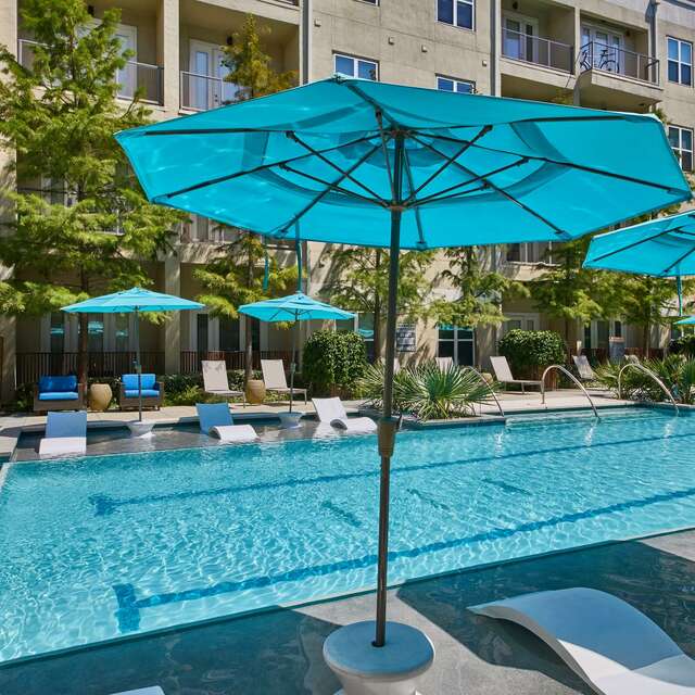 Closeup of the pool area with lounge chairs and blue umbrellas
