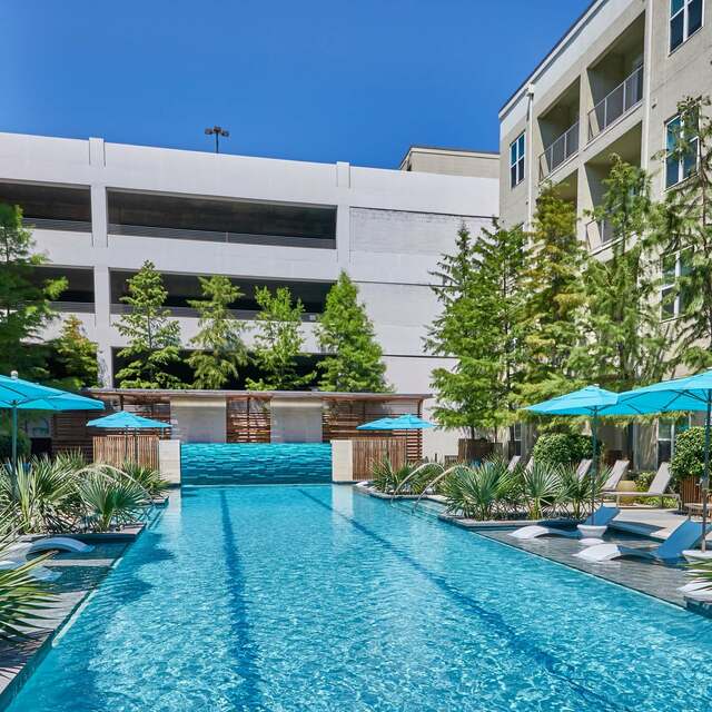 Beautiful pool area surrounded by trees and lounge seating