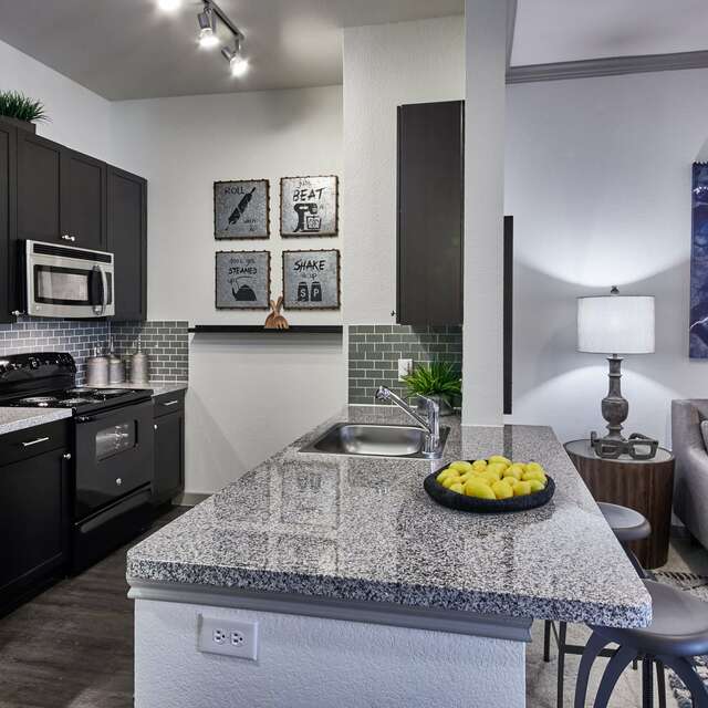 Kitchen with dark brown cabinetry, granite countertops, and a large island