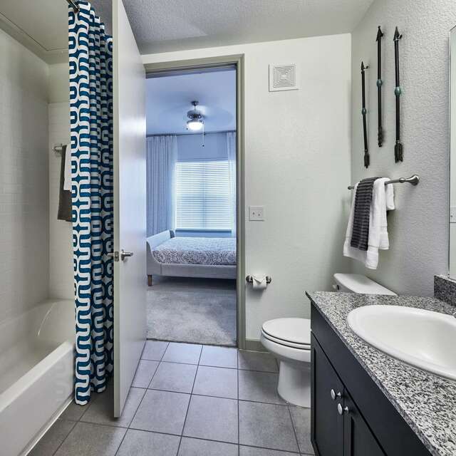 Bathroom with a single sink vanity, tub shower, and tile flooring