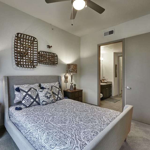 Primary bedroom suite with a grey fabric bed, nightstands, and a ceiling fan