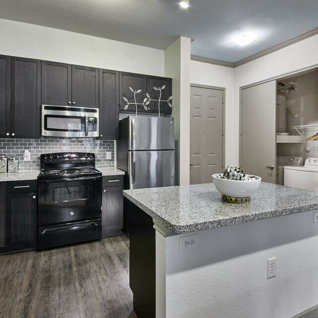 Fully equipped kitchen with brown cabinetry and a large island with granite countertops
