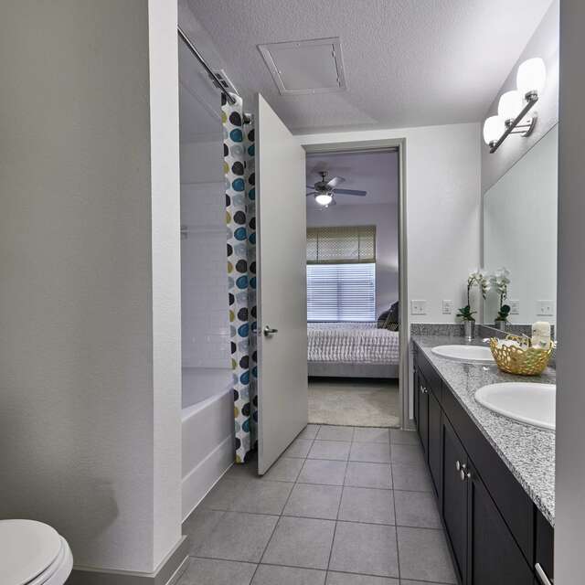 Bathroom with a large dual sink vanity and tub shower with a multi-colored shower curtain