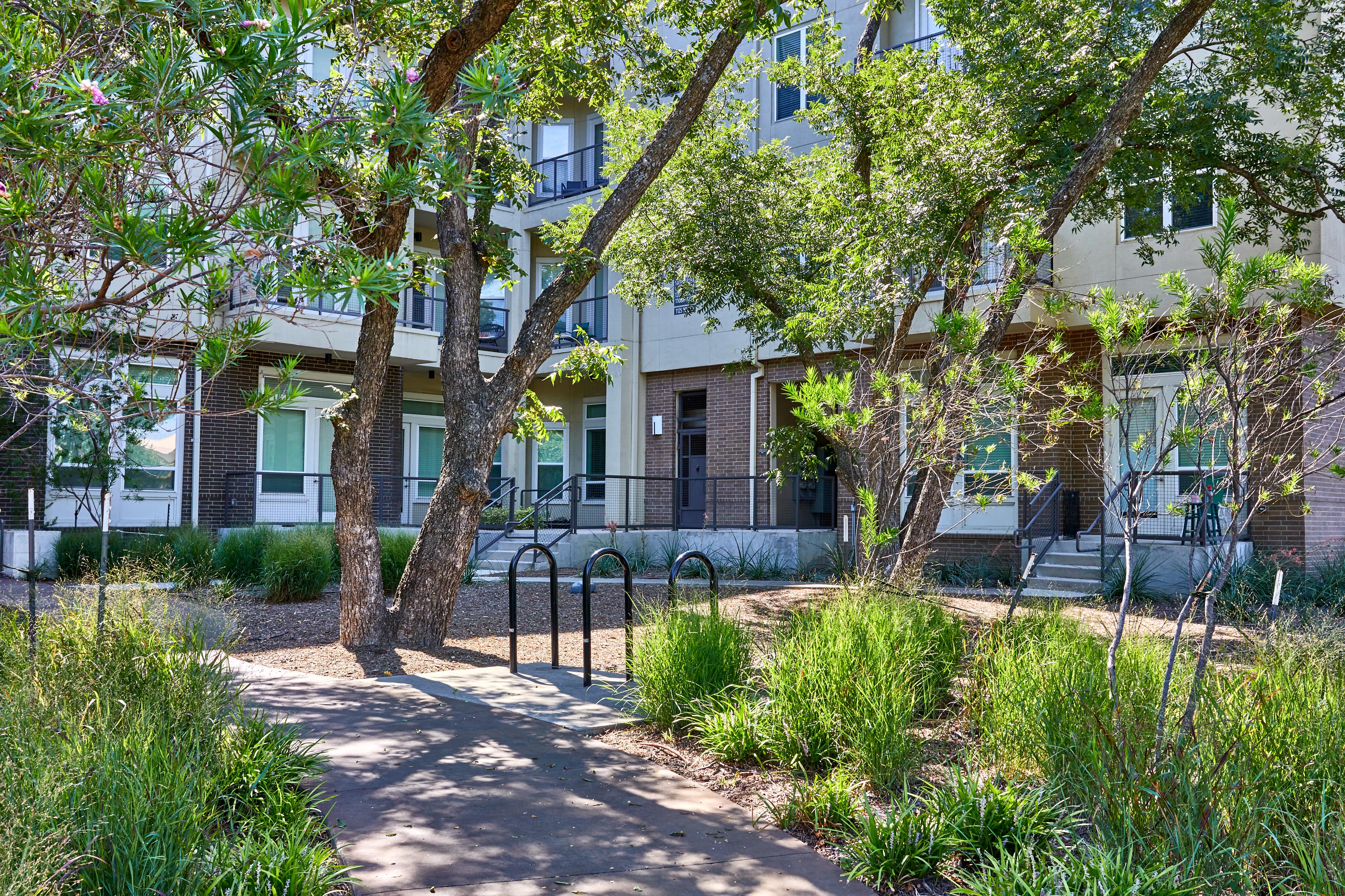 The exterior of the community with a walking path, trees, and bushes