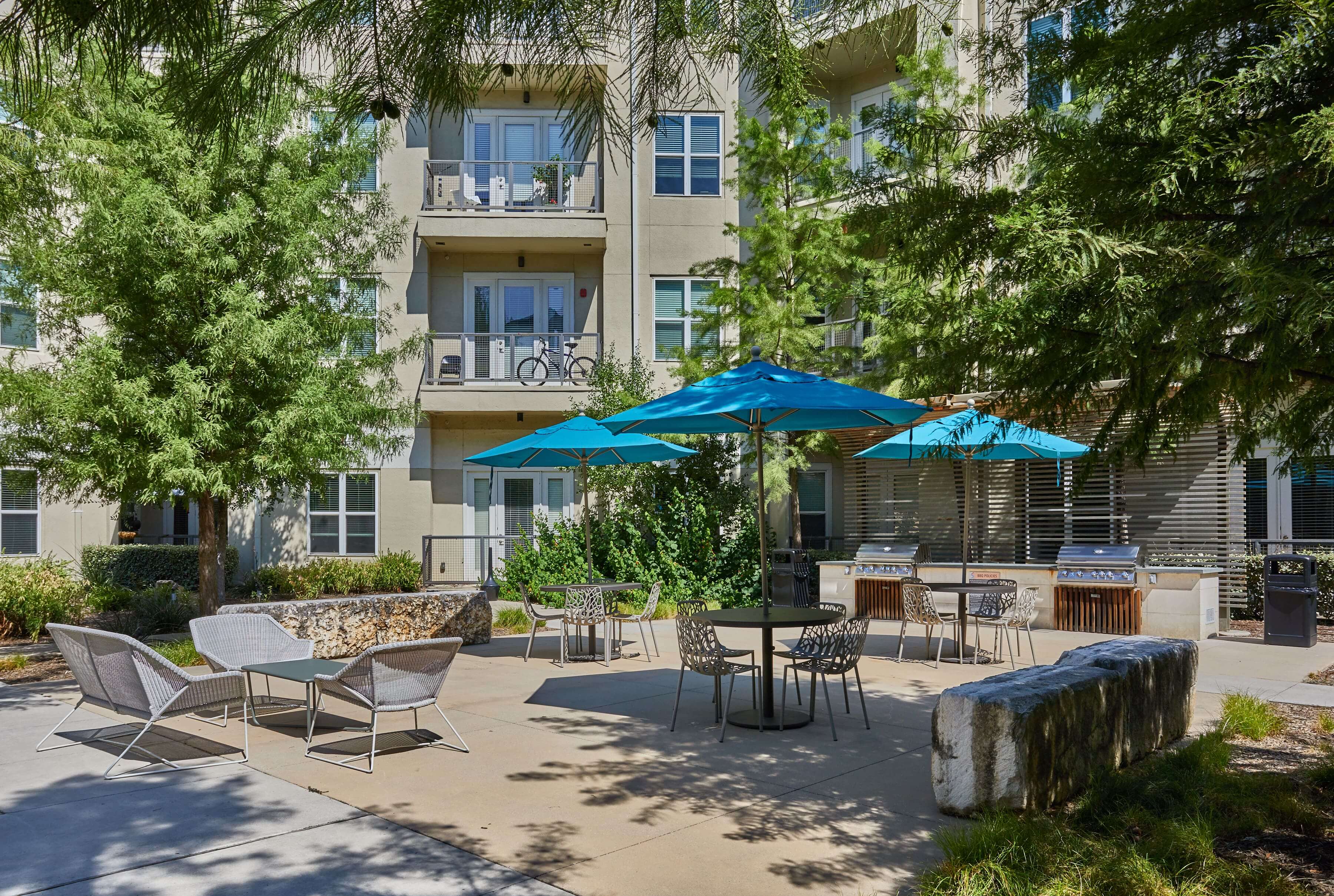 Community courtyard area with lounge seating and tables with umbrellas
