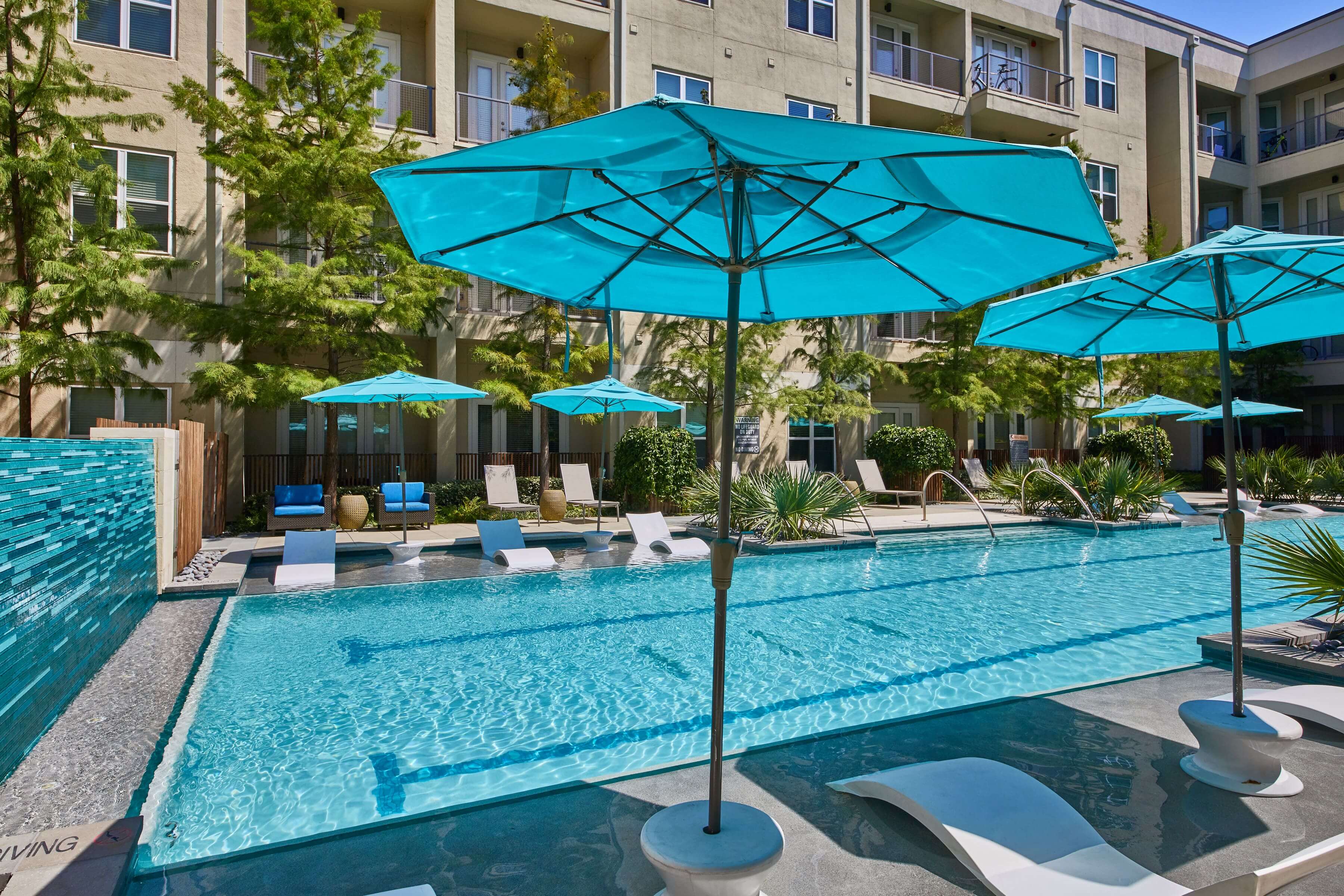Closeup of the pool area with lounge chairs and blue umbrellas