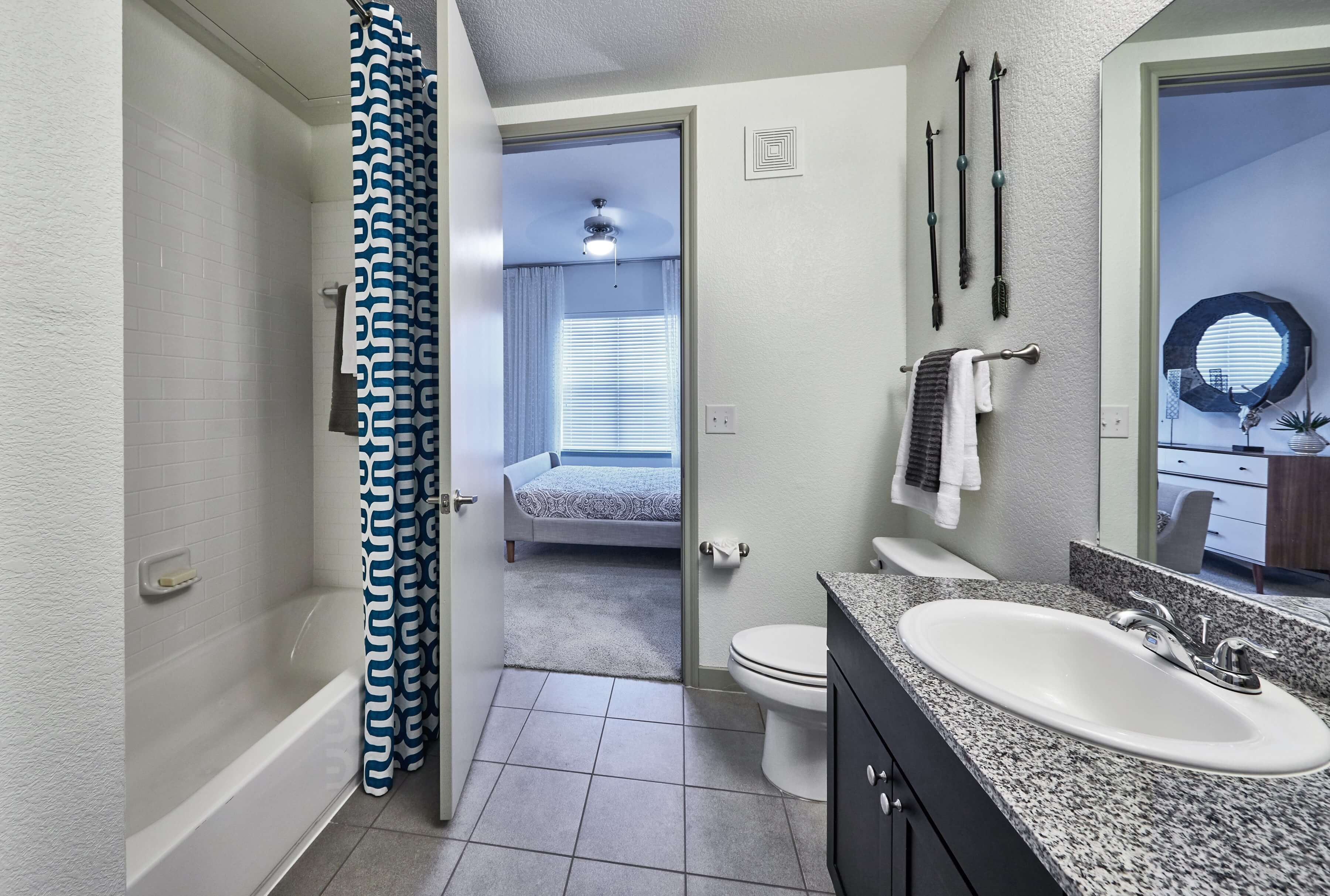 Bathroom with a single sink vanity, tub shower, and tile flooring