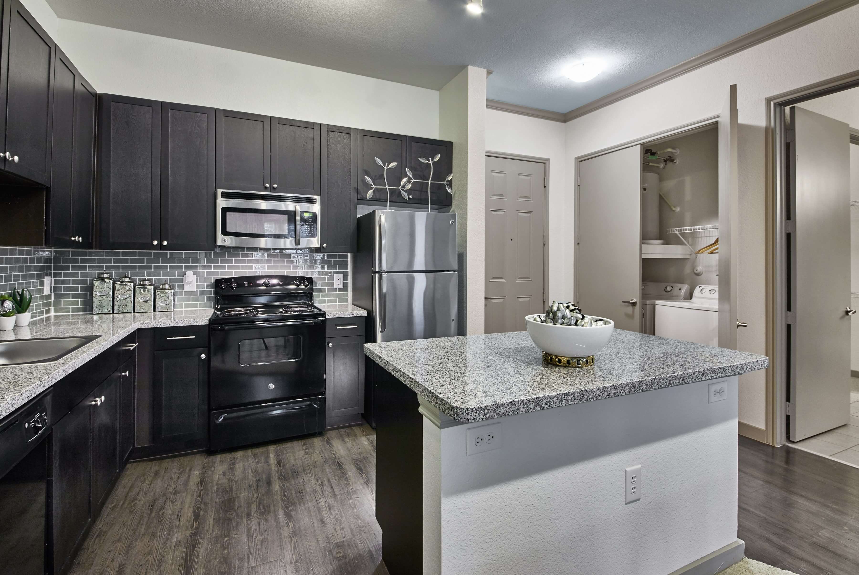 Fully equipped kitchen with brown cabinetry and a large island with granite countertops