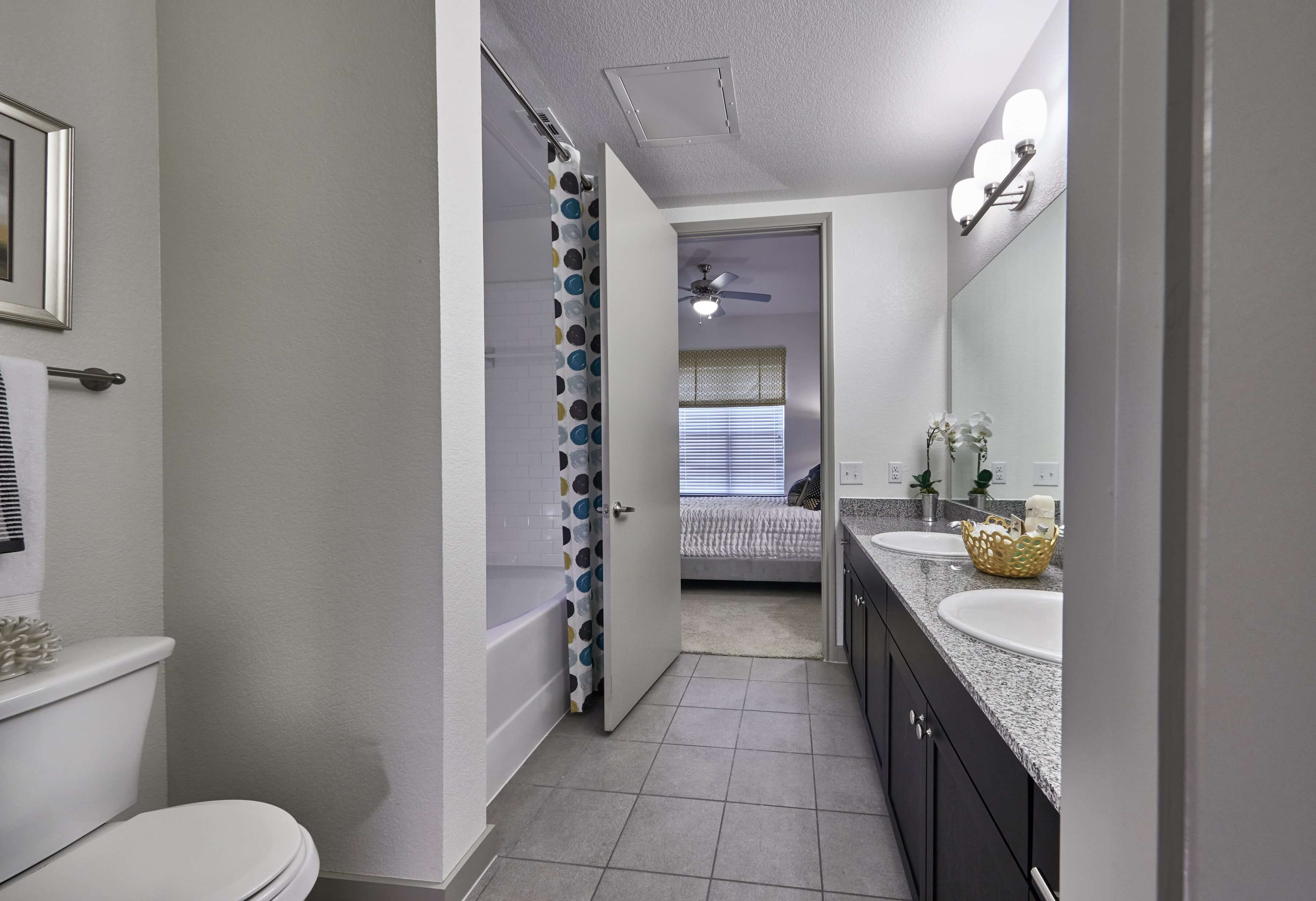 Bathroom with a large dual sink vanity and tub shower with a multi-colored shower curtain